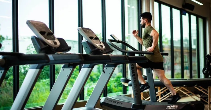 Person running on a commercial treadmill in a well-maintained gym facility